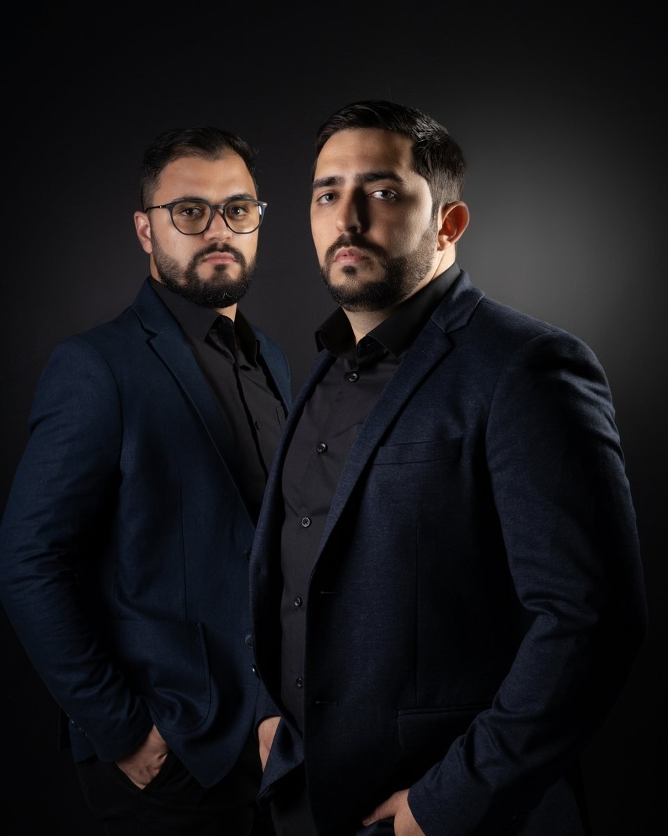 Dois integrantes da equipe da Encaixe, de blazer azul-marinho, em retrato de estúdio