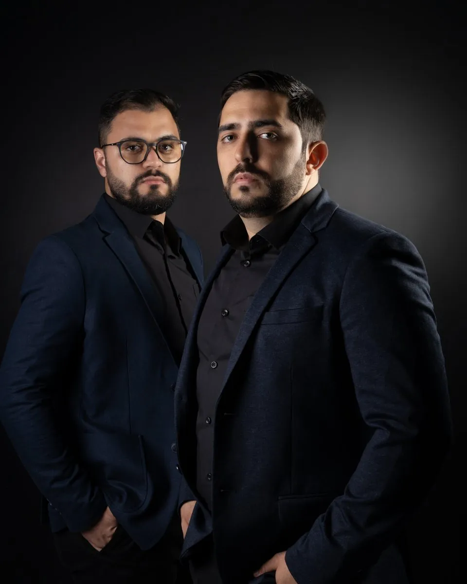 Dois integrantes da equipe da Encaixe, de blazer azul-marinho, em retrato de estúdio